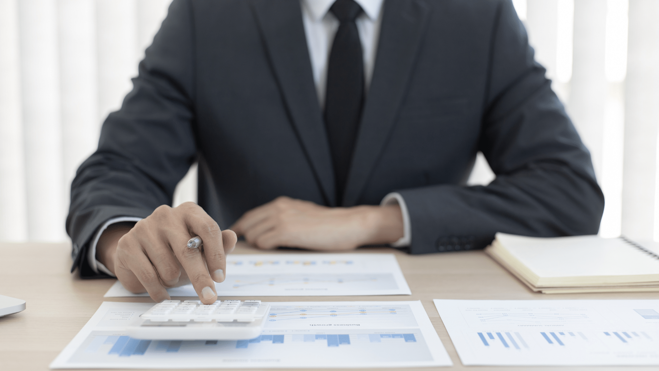 Financial advisor calculating Backdoor Roth IRA contributions while analyzing investment charts and retirement planning data at a desk.